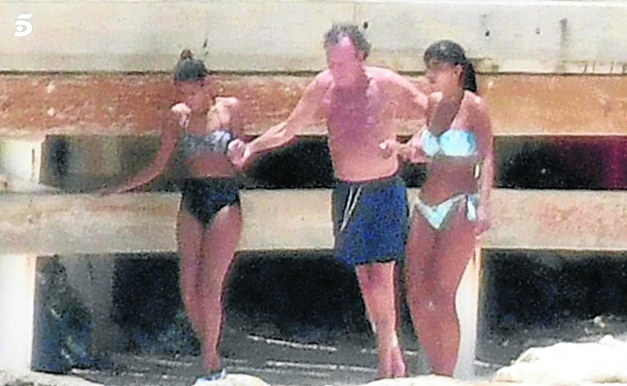 Julio Iglesias, ayudado por dos jóvenes en la playa.