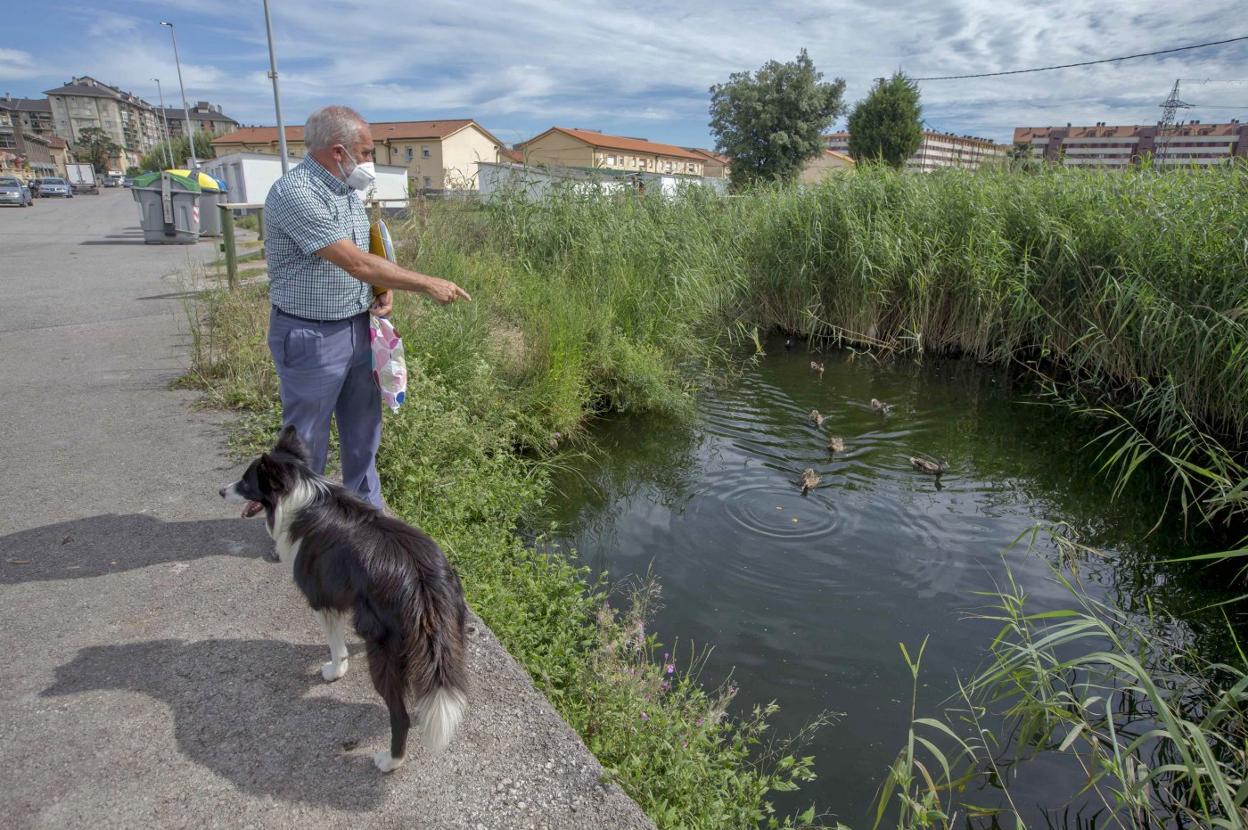 Nobel Lado, junto a su perro Lagun, señala la zona de la ría donde se producen los vertidos de aguas fecales.