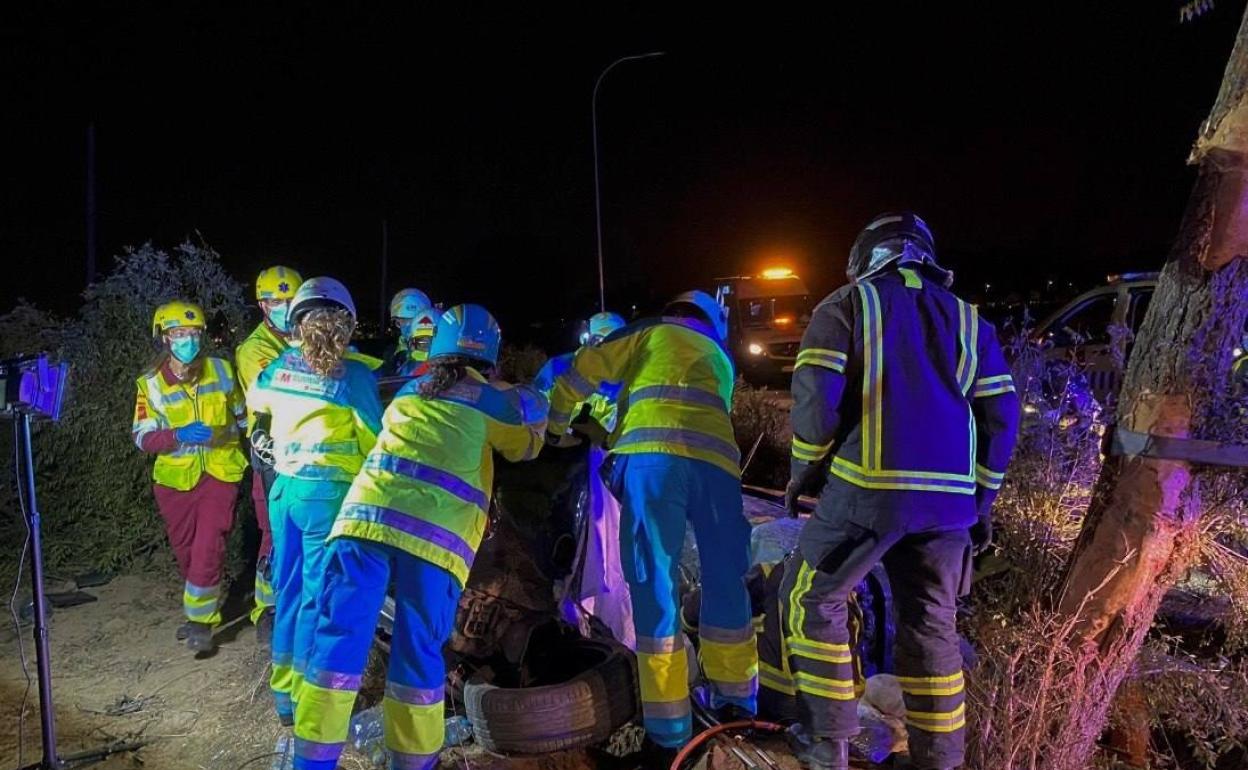 Los sanitarios y los bomberos rescatan los cuerpos del coche accidentado durante la madrugada del lunes, en Mostoles (Madrid).