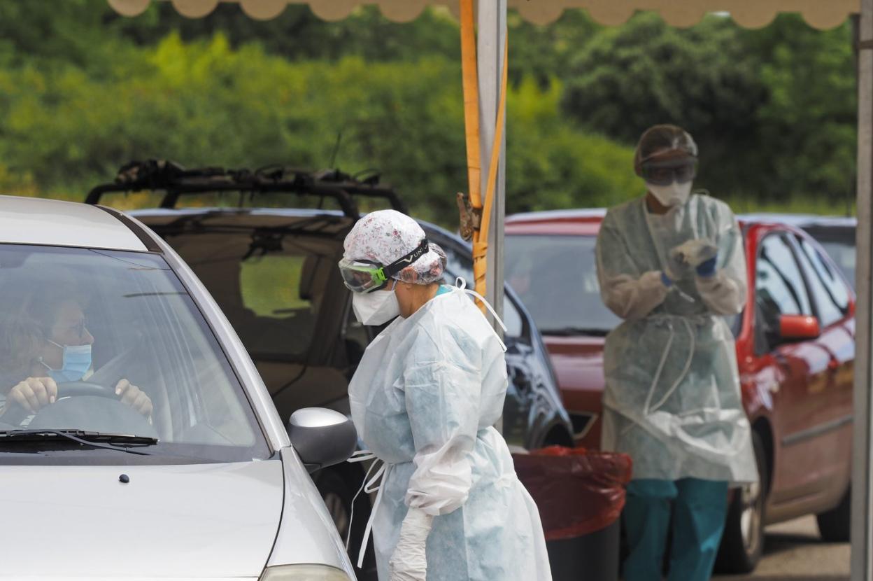 Imagen del 'coroauto' instalado en Liencres, con dos sanitarios atendiendo la cola. 