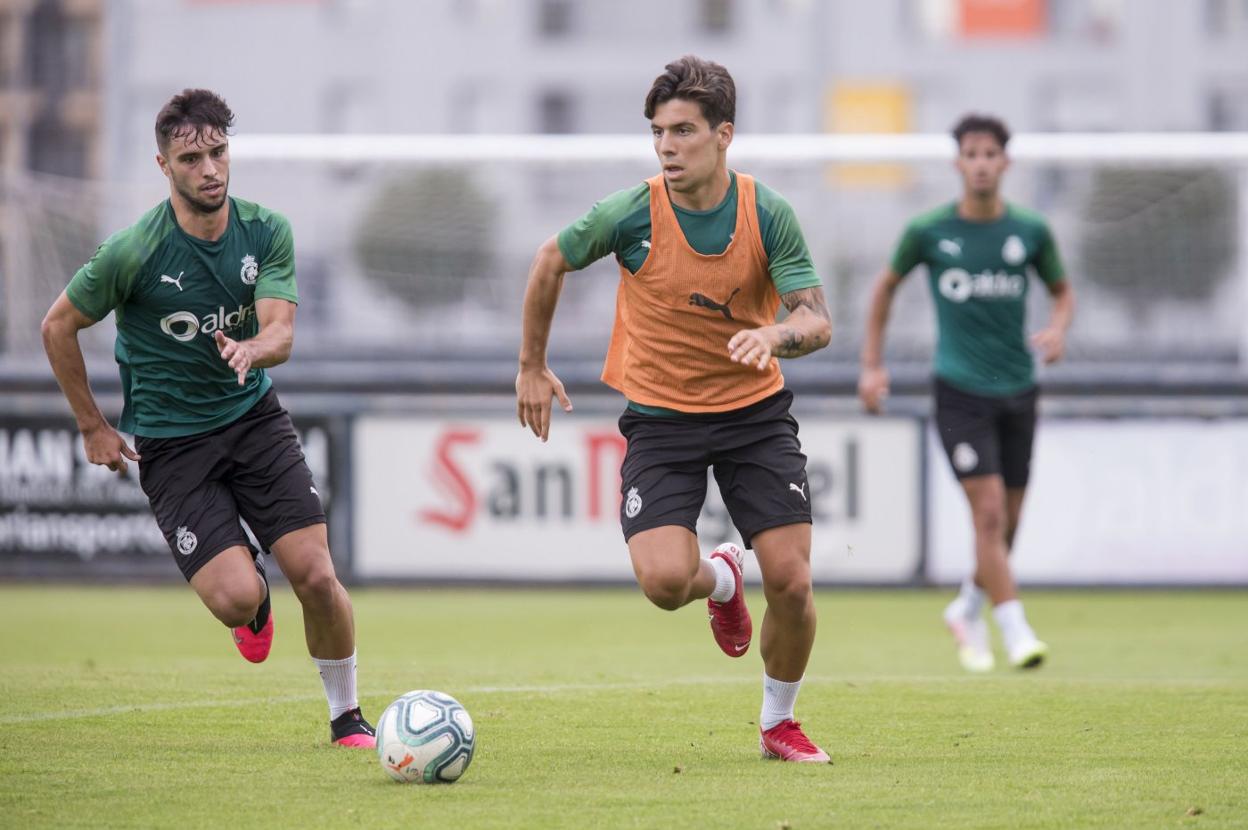 Martín Solar conduce el balón ante la presencia de Miguel Goñi, dos de los canteranos del Racing. 