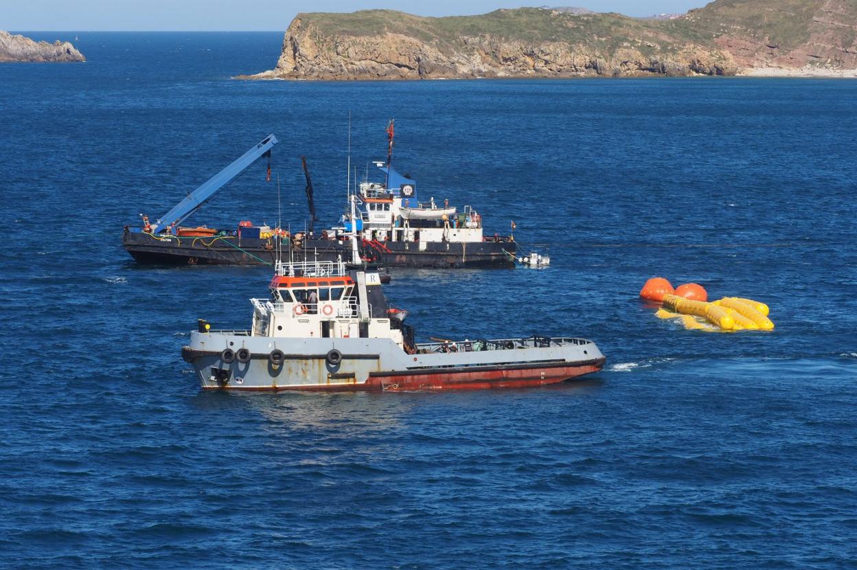 El barco encargado del reflotamiento, al fondo, junto al remolcador que traslada la draga hasta Gijón. 