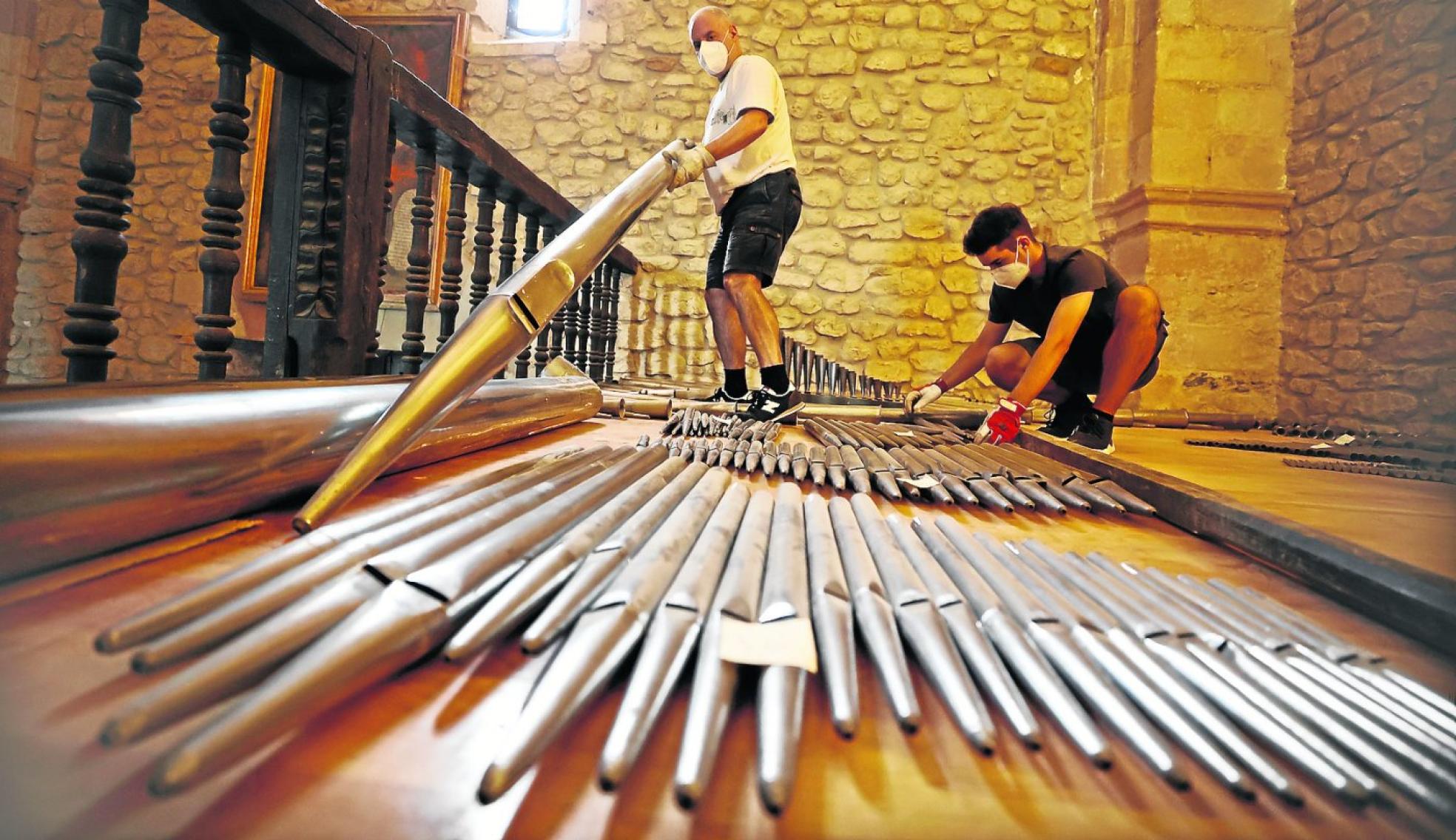Dos expertos trabajan con los tubos del órgano (tiene 800) en el interior de la iglesia de Terán. 