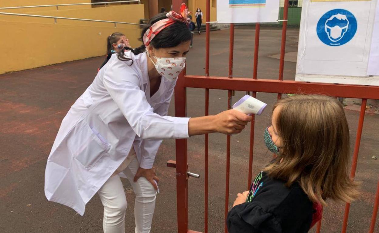 Una profesora toma la temperatura a una alumna, hoy, en el colegio José María de Pereda de Torrelavega.