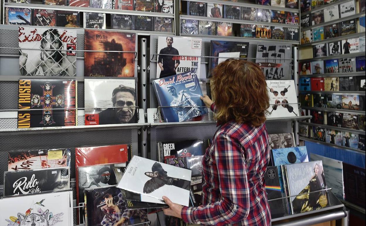 Una empleada coloca unos vinilos en las estanterías de una tienda de discos.