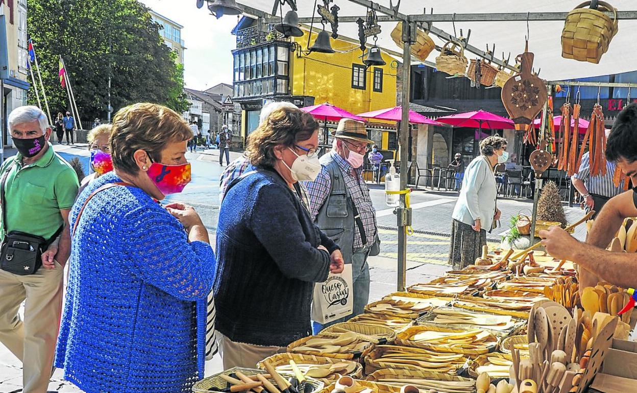 Varias personas compran en unos de los puestos de artesanía