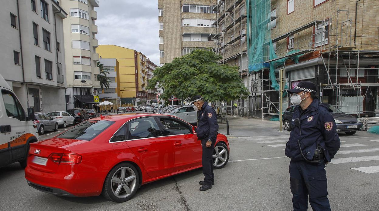 Un vehículo circula por el barrio junto a uno de los controles establecidos por agentes de la Policía Local.