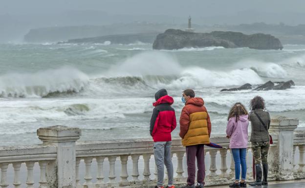 Imagen. Cuatro personas observan el temporal marítimo desde la entrada a un arenal de la capital. 