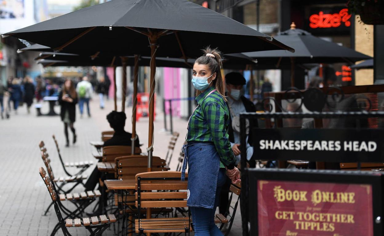 Una camarera con pocos clientes en una terraza de Londres. 