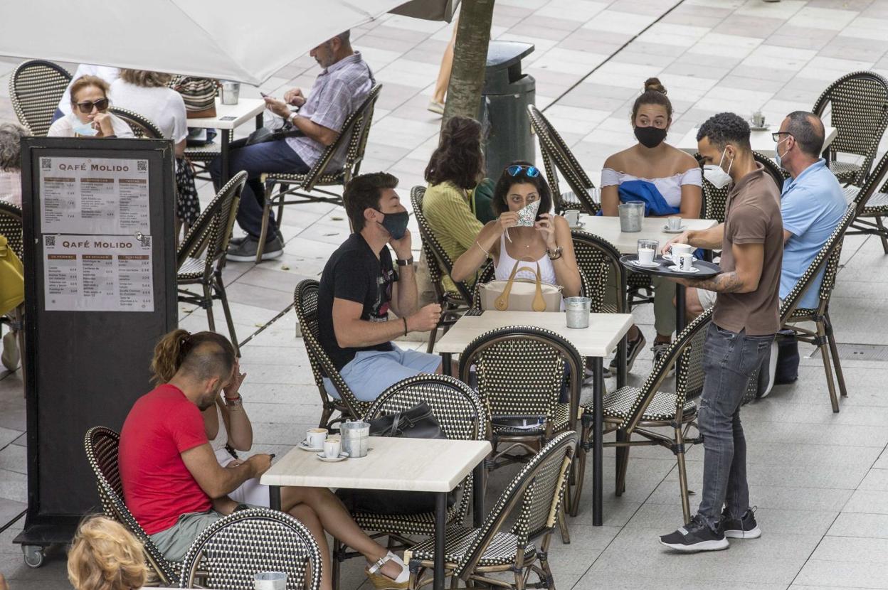 Un camarero atiende a los clientes sentados en la terraza de un establecimiento hostelero del centro de Santander.