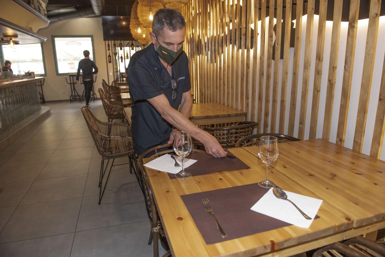 Víctor Merino, del restaurante La Bodega, en El Sardinero, ayer, prepara las mesas para los comensales. 