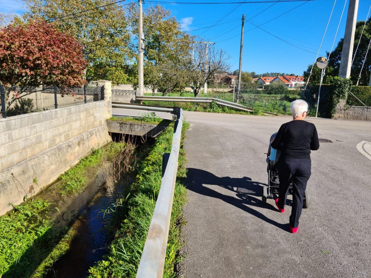 María Ángeles Arce, vecina del pueblo de Camargo, pasea con su nieto, ayer, en el barrio Ladredo junto al cauce del arroyo. dm