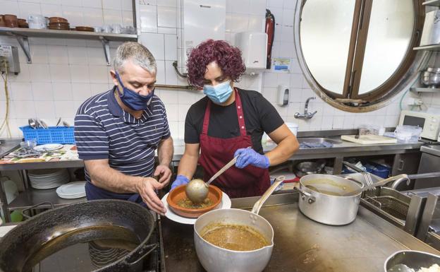 Juan Ramón Isabel, del Peña Candil, prepara un menú con una empleada en la cocina del local. 