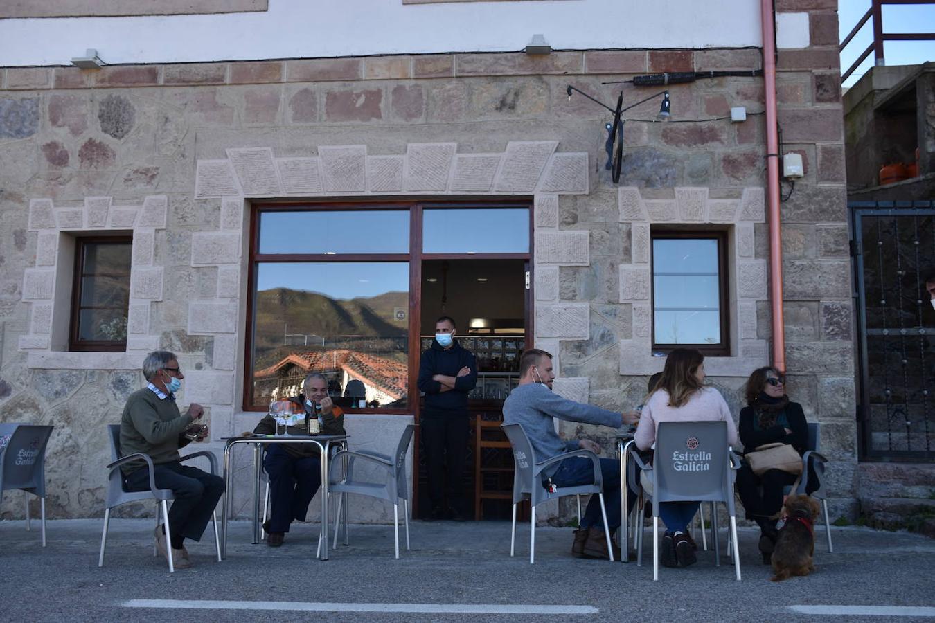 Jesús y Manuel, en la terraza del bar El Refugio del pueblo de La Lastra (Tudanca). En la mesa contigua está Ana, la nueva farmacéutica que llegó al municipio el pasado viernes, junto a su familia