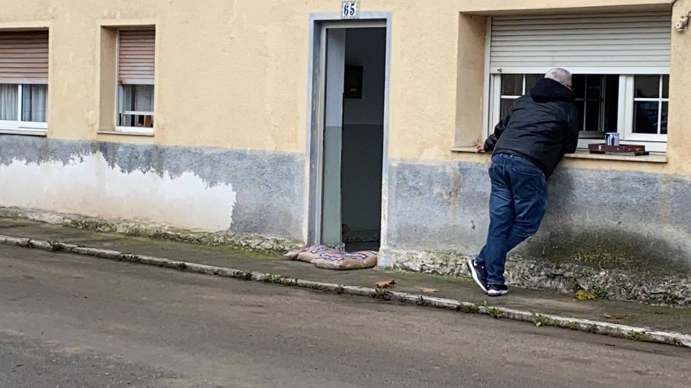 Operarios clavan tablones y extienden una capa de tierra a modo de dique para evitar que el agua vuelva a inundar el barrio de Santiago el Mayor (Nueva Montaña), mientras el vecindario sigue limpiando el barro, colocando sacos a las puertas de sus casas y los bomberos achican el agua acumulada en bajos y garajes.