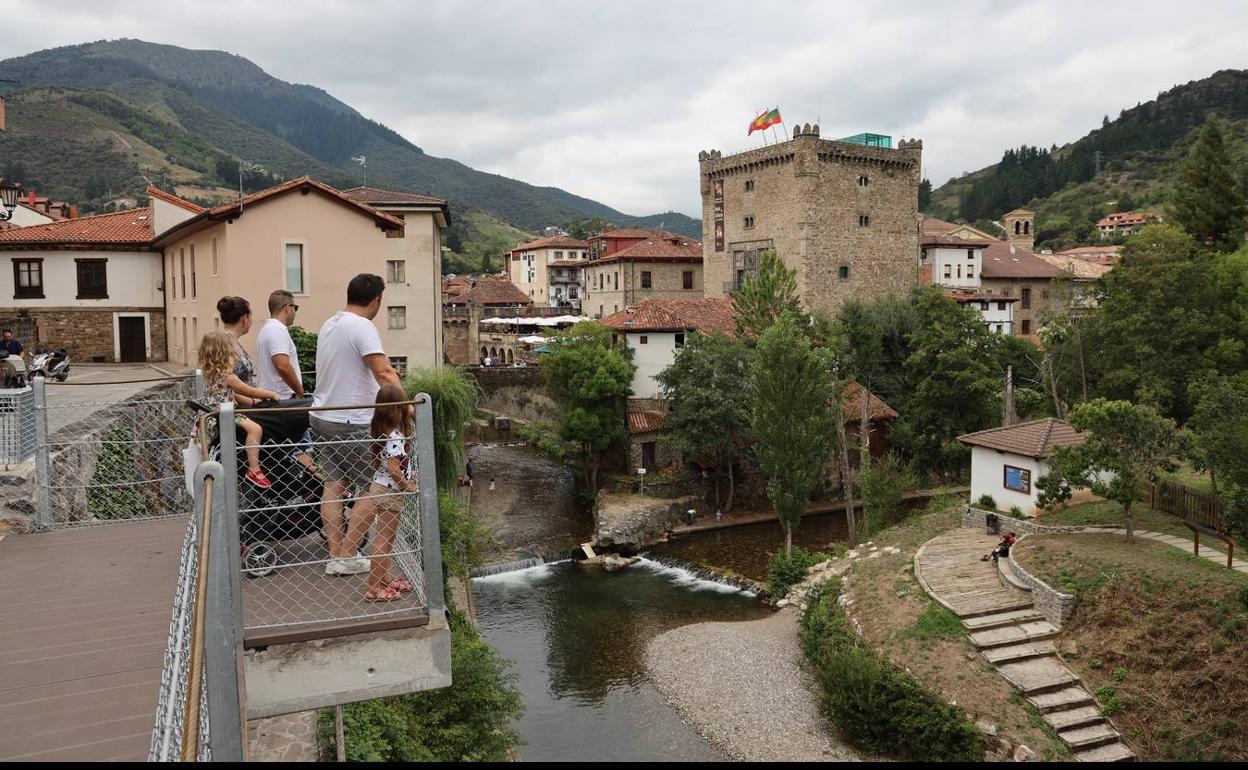 Una familia de turistas contempla la Torre del Infantado de la villa de Potes desde el mirador sobre el río Deva 