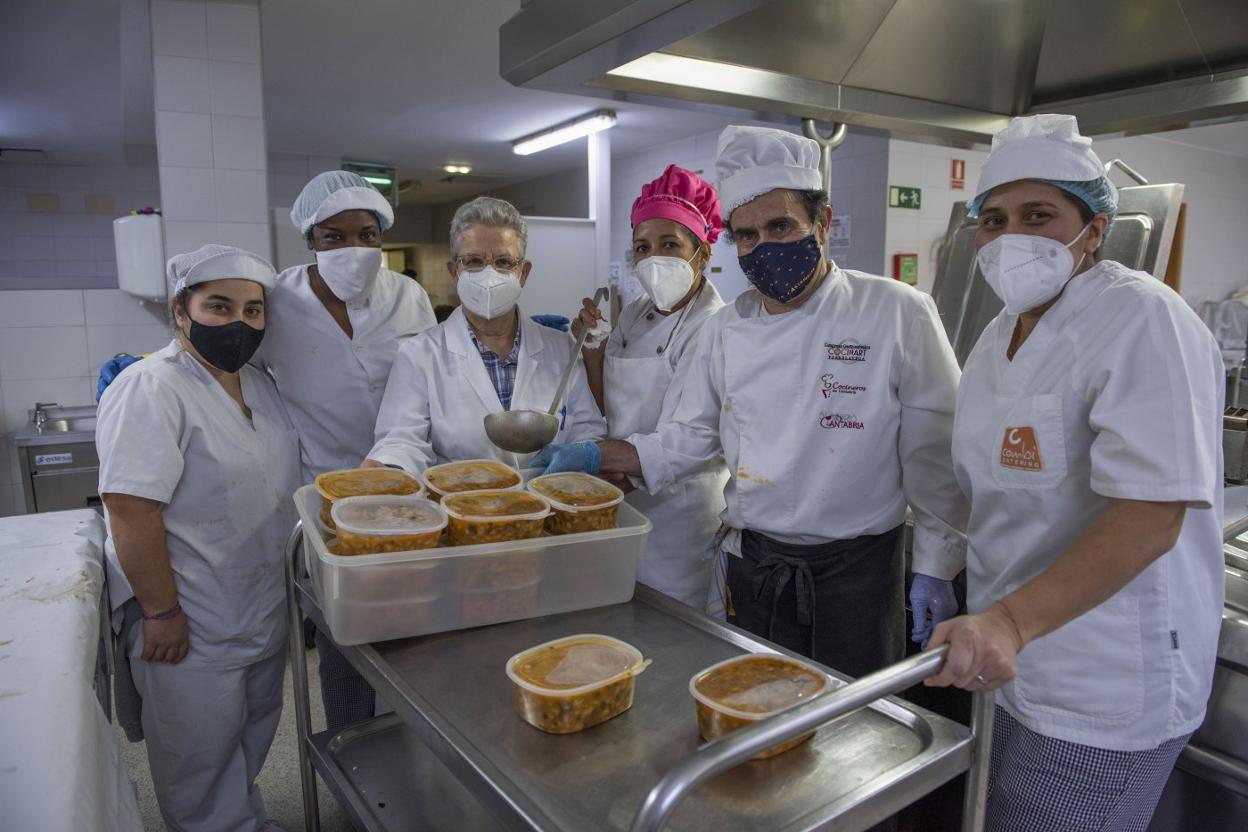 El cocinero José Ángel García (segundo por la derecha), en los fogones de la Cocina Económica, este martes, con las raciones de cocido montañés para llevar. 