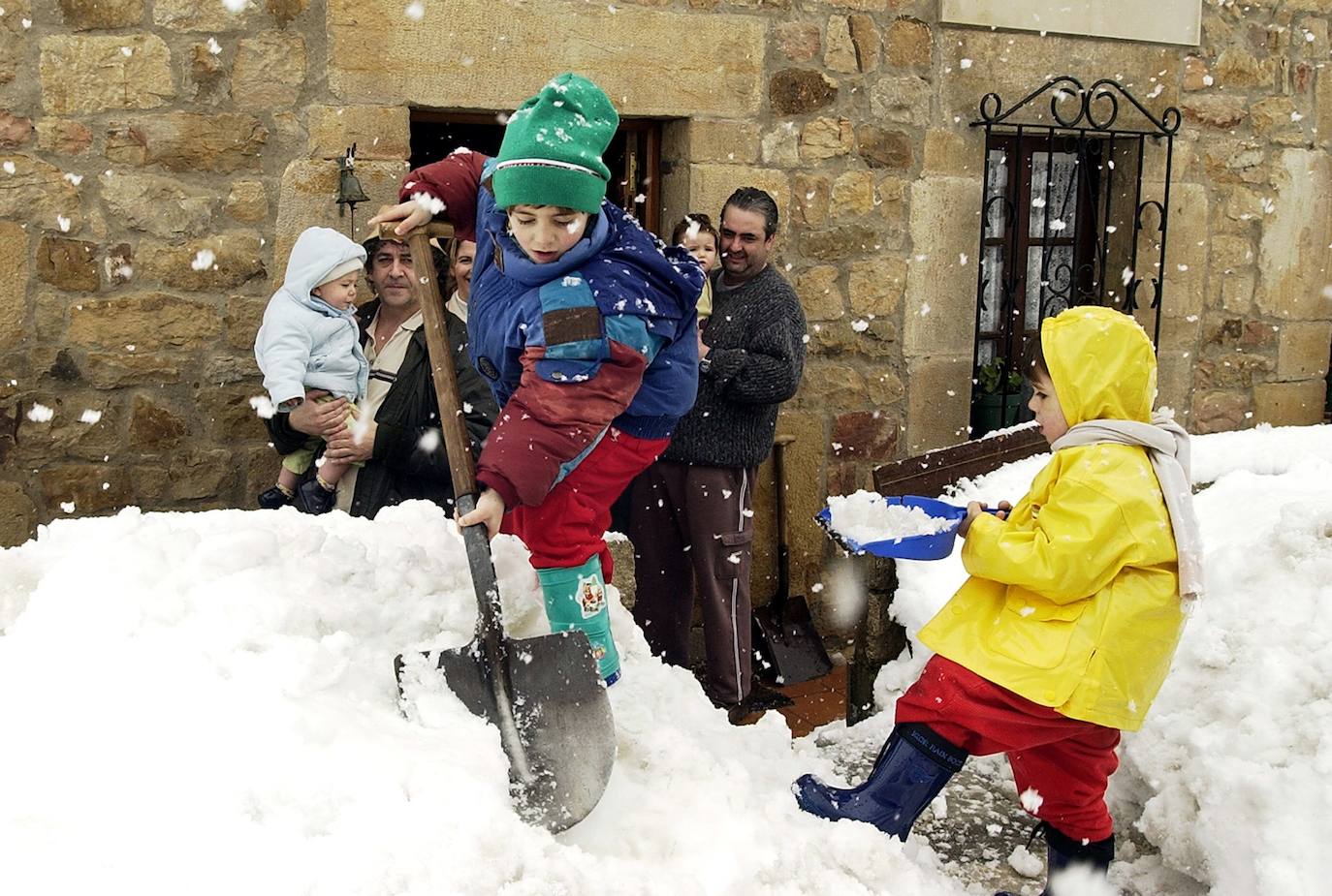 Febrero de 2004. Unos niños se divierten retirando nieve de la puerta de su casa, en los Pandos.