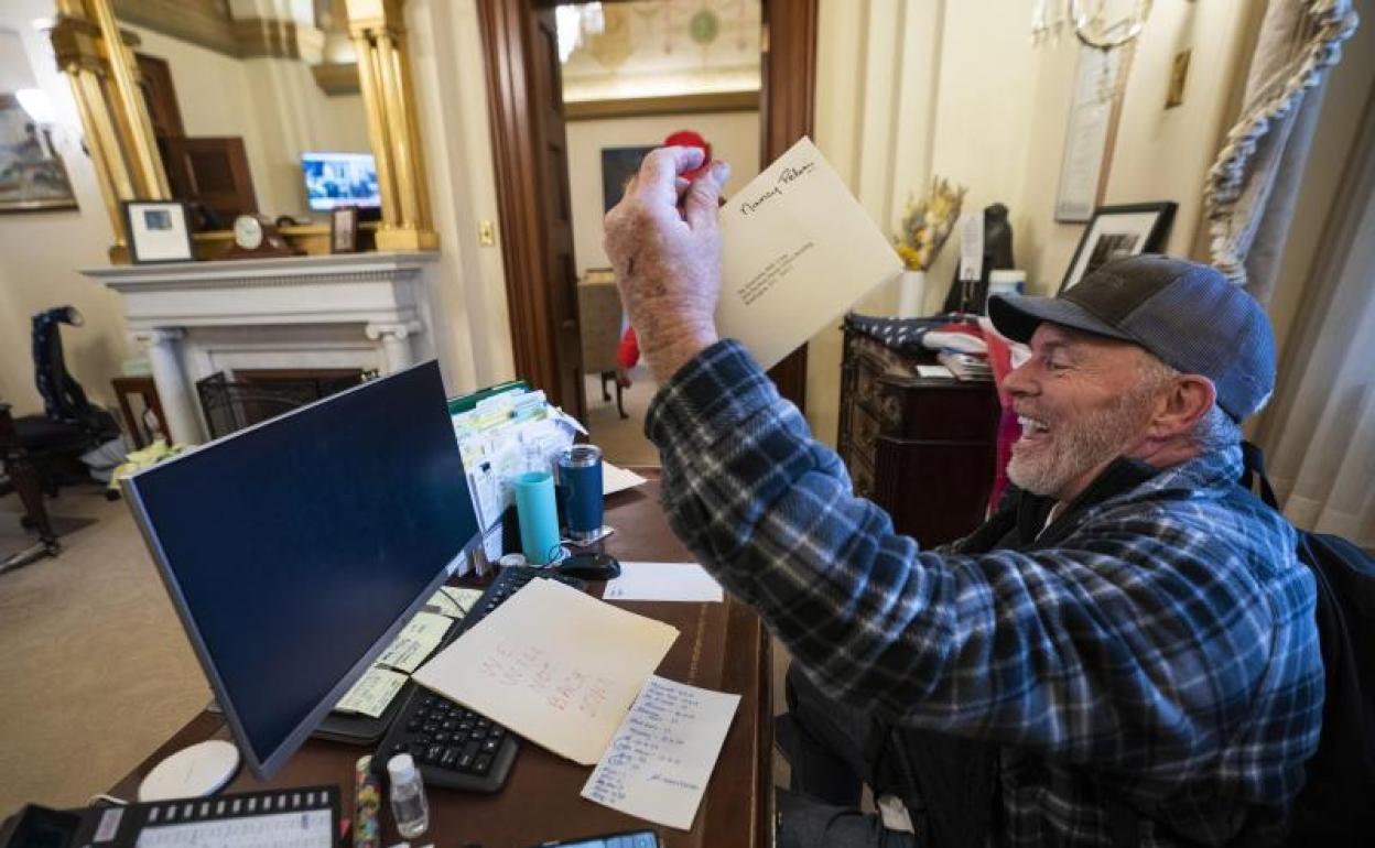 Un partidario del presidente Donald Trump se sienta en el escritorio de la presidenta de la Cámara de Represetantes, Nancy Pelosi 