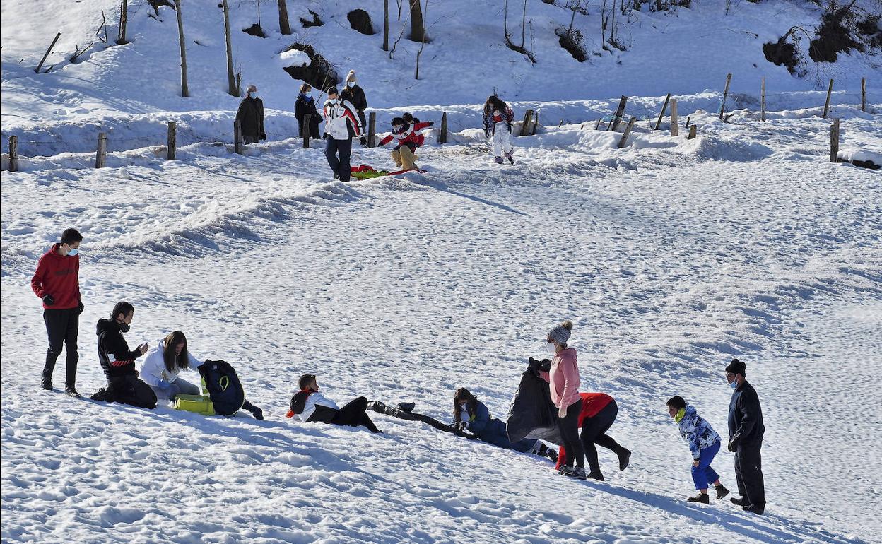 Pequeños y mayores juegan con la nieve en San Roque de Riomiera.