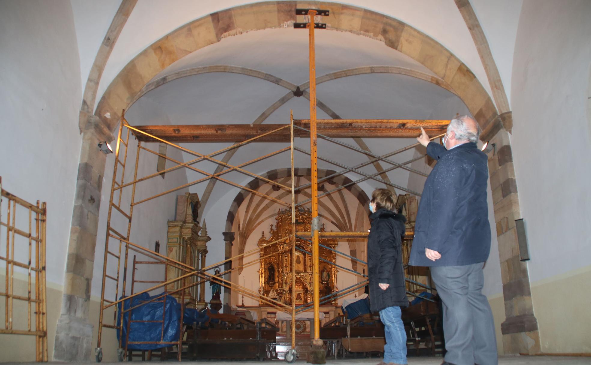 El párroco y una de las vecinas observan la enorme grieta surgida en la bóveda y que ha mantenido el templo cerrado 