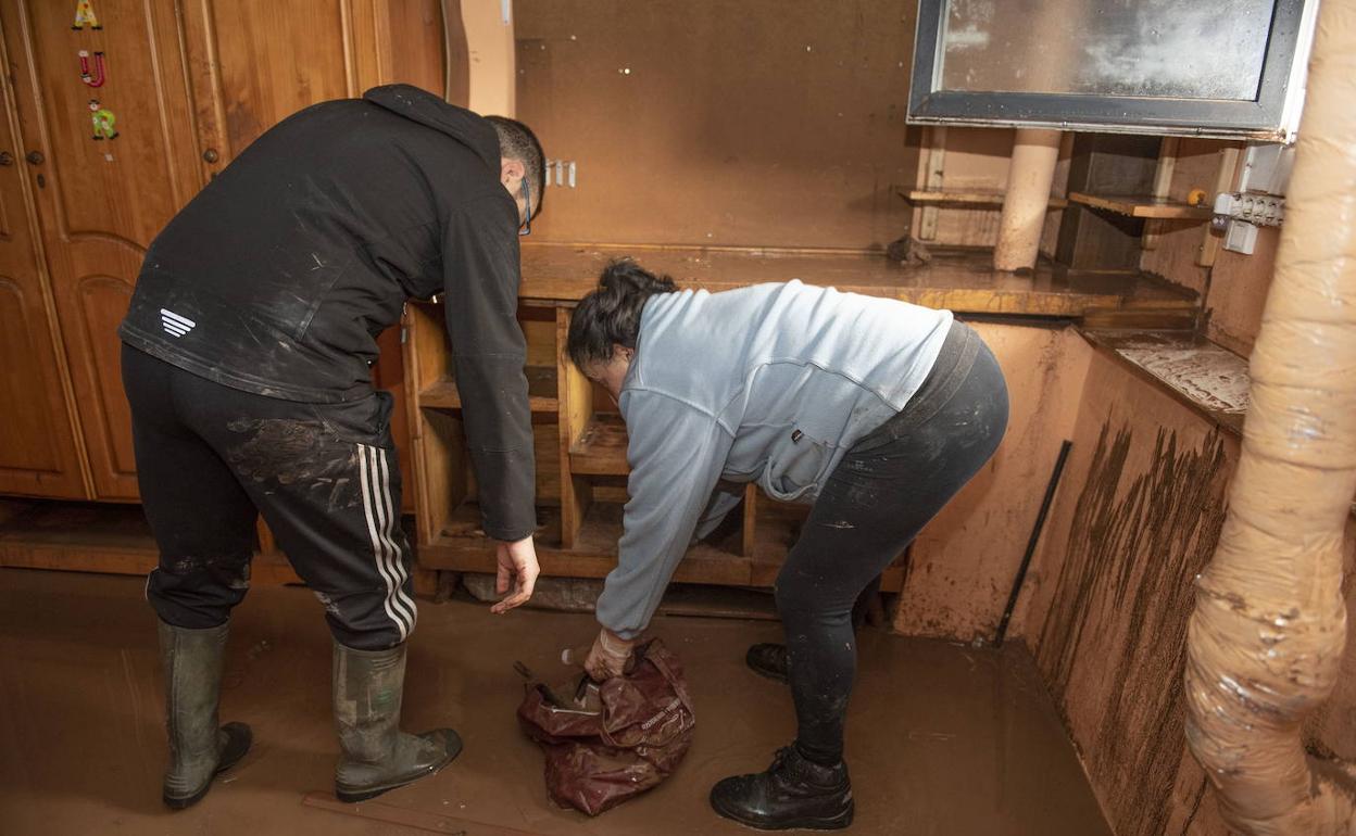 Una familia limpia los restos del barro y agua que provocaron las inundaciones de diciembre de 2019 en Reinosa.