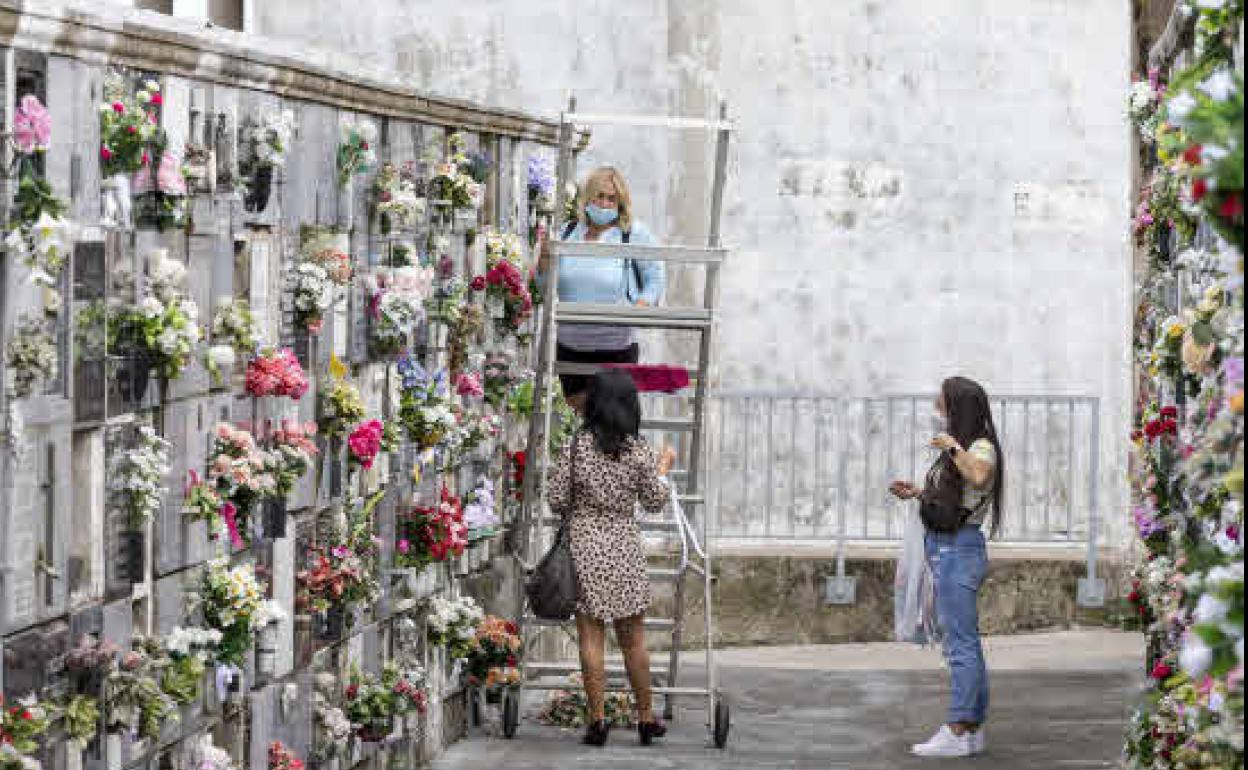 Tres mujeres colocan flores en el día de todos los Santos, en el cementerio de Ciriego