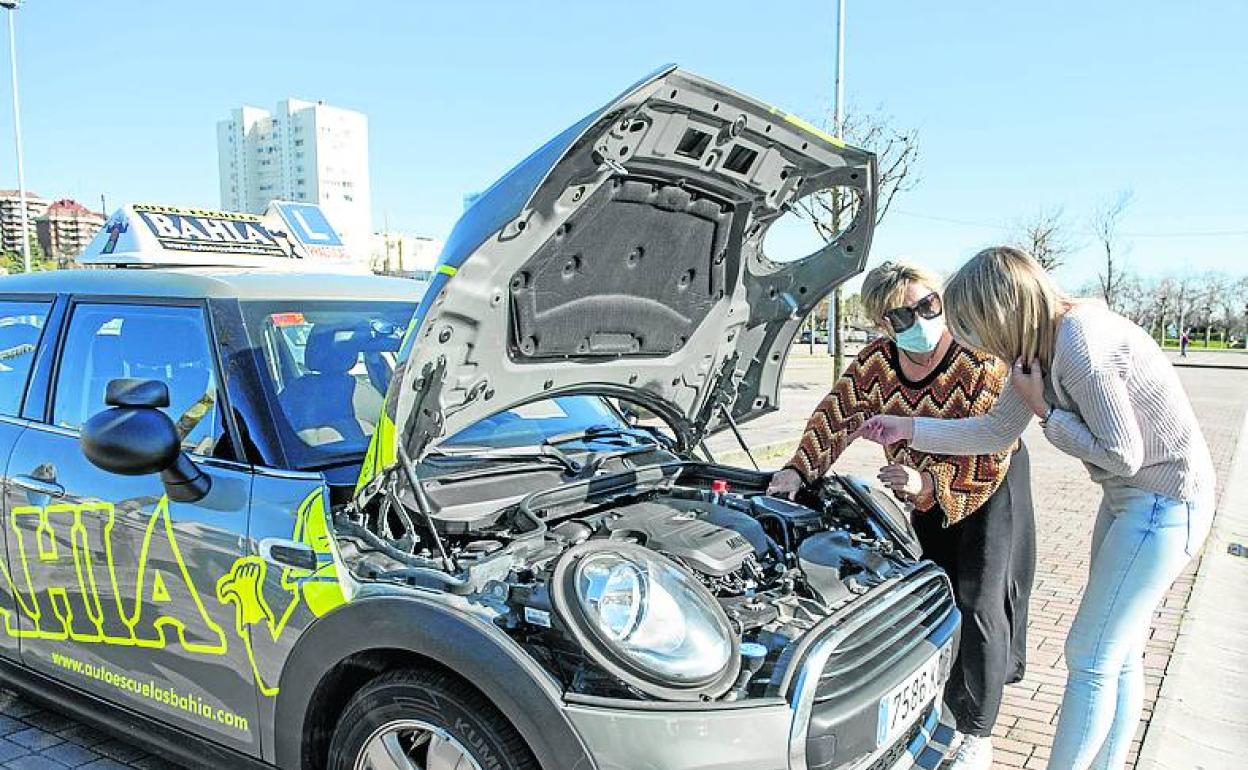 Alumna y profesora observan el motor del vehículo. 