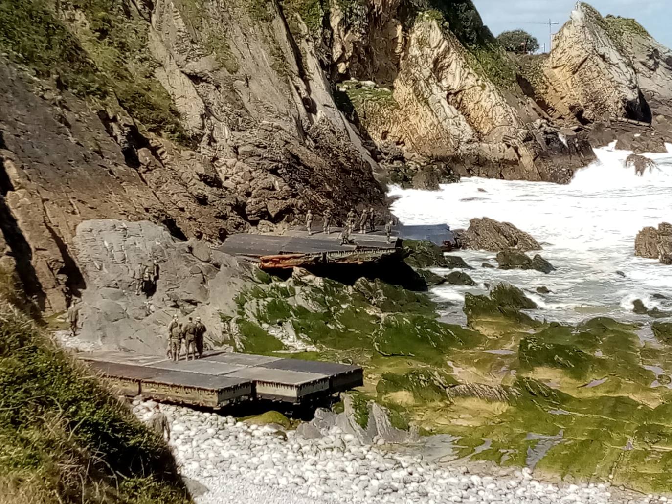 Los soldados retiran partes de los pontones encallados en la cala del Pocillo del Fraile para aligerar la maniobra de retirada de estas estructuras, desprendidas del puerto flotante instalado por el Ejército en unas maniobras desplegadas en Castro Urdiales. Otras piezas han acabado varadas en la playa de Brazomar, generando gran expectación.