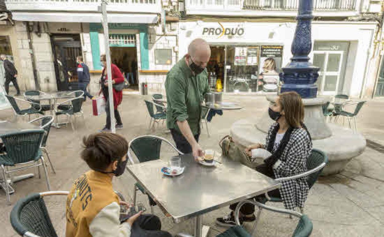 Un hostelero sirve a dos clientes en la terraza de un bar en Santander