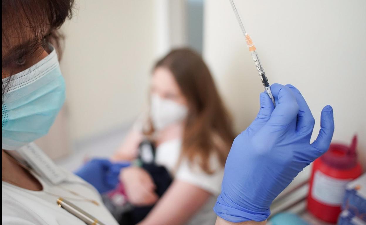 Una enfermera se dispone a administrar una vacuna frente al covid-19 a una joven. 
