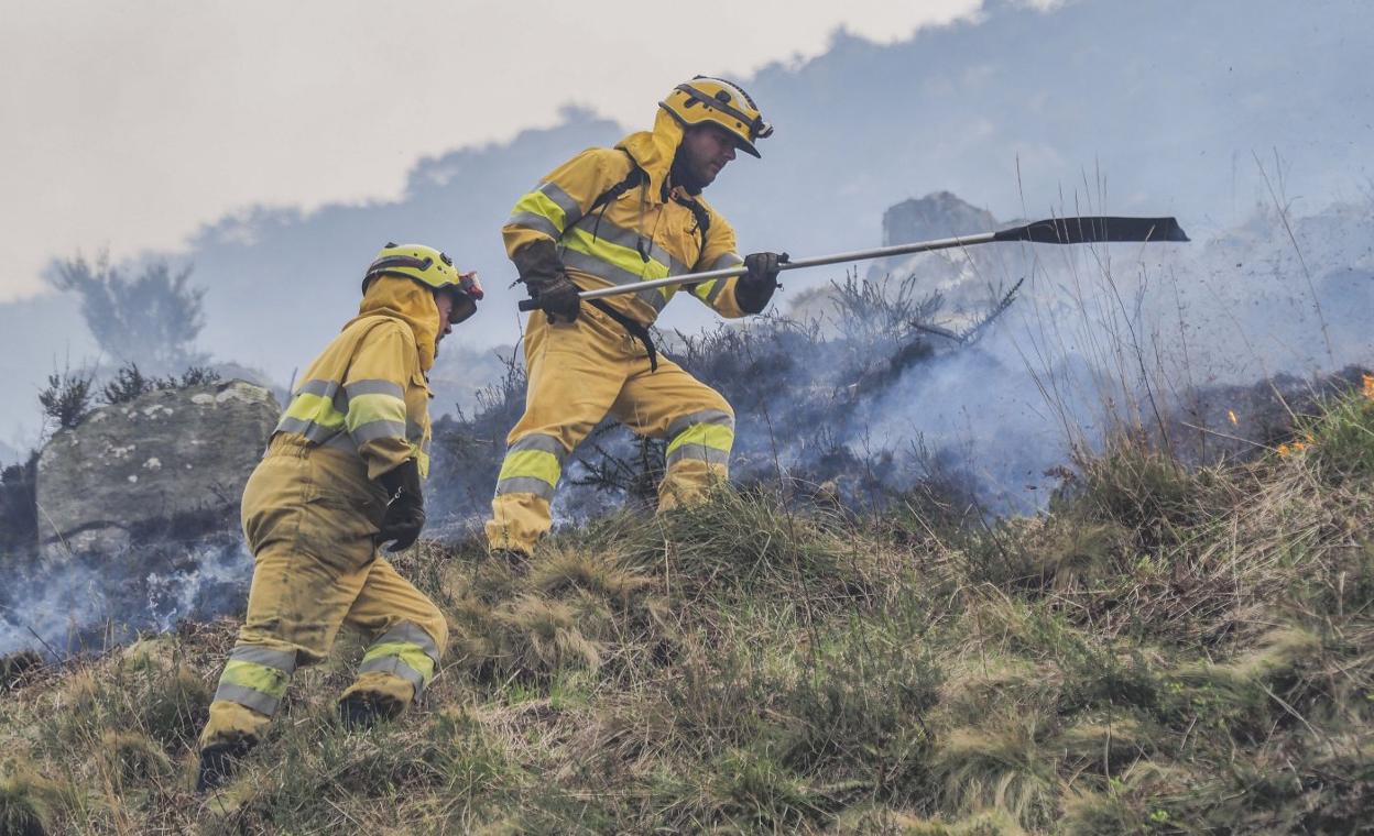 Dos agentes de Montes en pleno trabajo, ayer, durante las labores de extinción del fuego en Vega de Pas. 