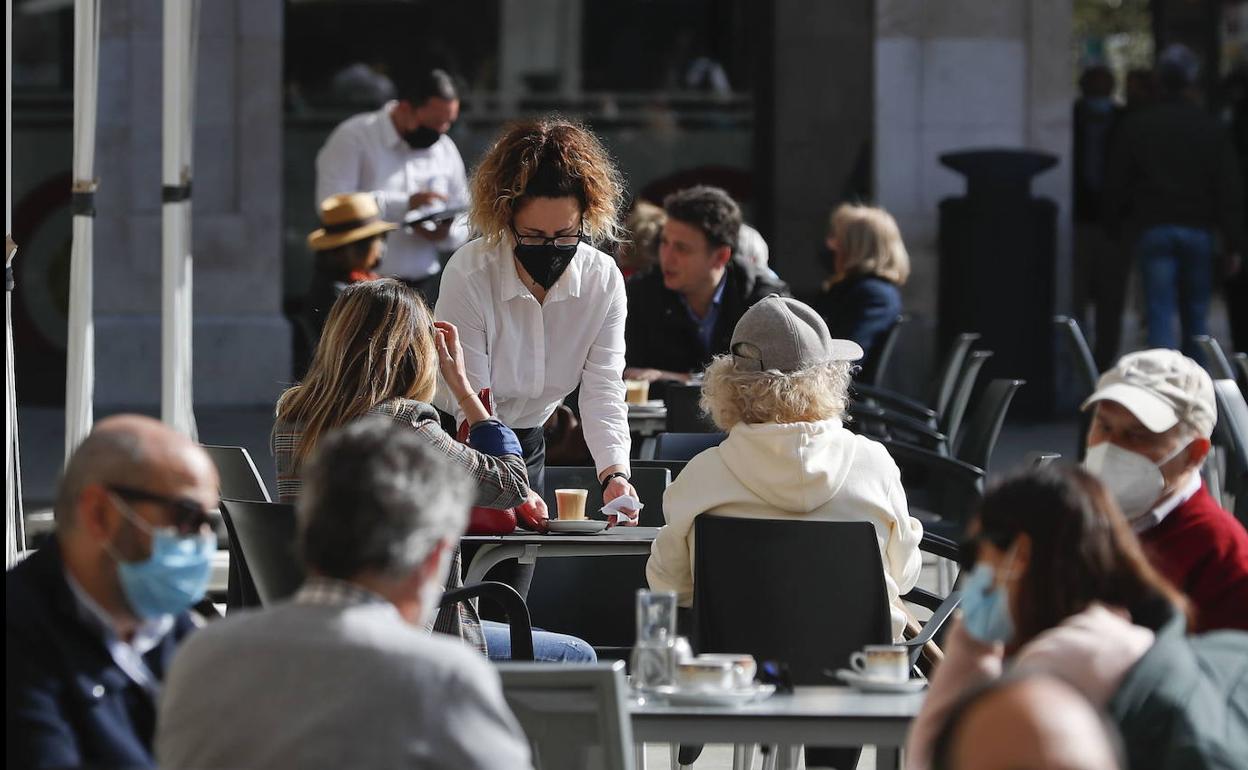 Una camarera atiende a unas clientas en una terraza de la Plaza Porticada.