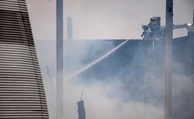 Un bombero refresca la zona afectada por el fuego en el polígono industrial de Seseña (Toledo).