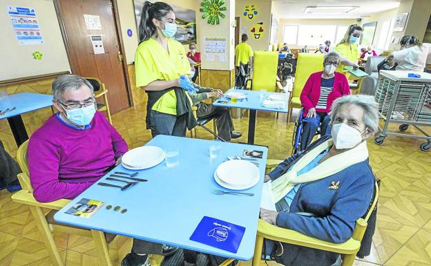 Las personas mayores de la residencia San Cipriano, en Santa Cruz de Bezana, esperan la hora de la comida separados en mesas y repartidos por grupos. 