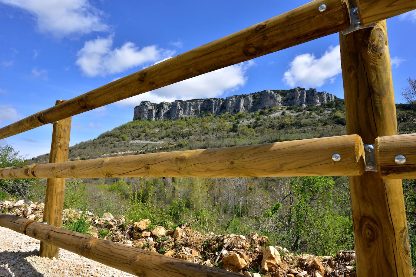 Peña de Dulla vista a través de una de las barandillas de madera colocadas como defensa en los tramos del trayecto que lo requieren