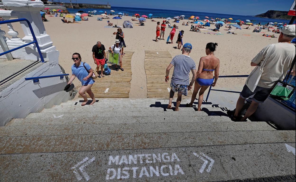 Los bañistas en las escaleras de acceso a la playa de Comillas. 