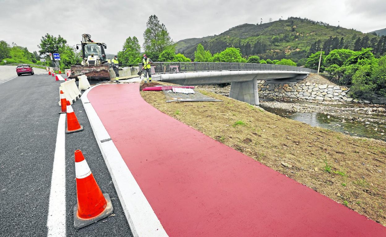 Dos operarios realizan los últimos trabajos en el flamante puente sobre el Saja que une la carretera con las praderías de Monte Aa. 