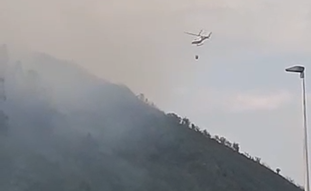 El helicóptero llevando agua para apagar el fuego.