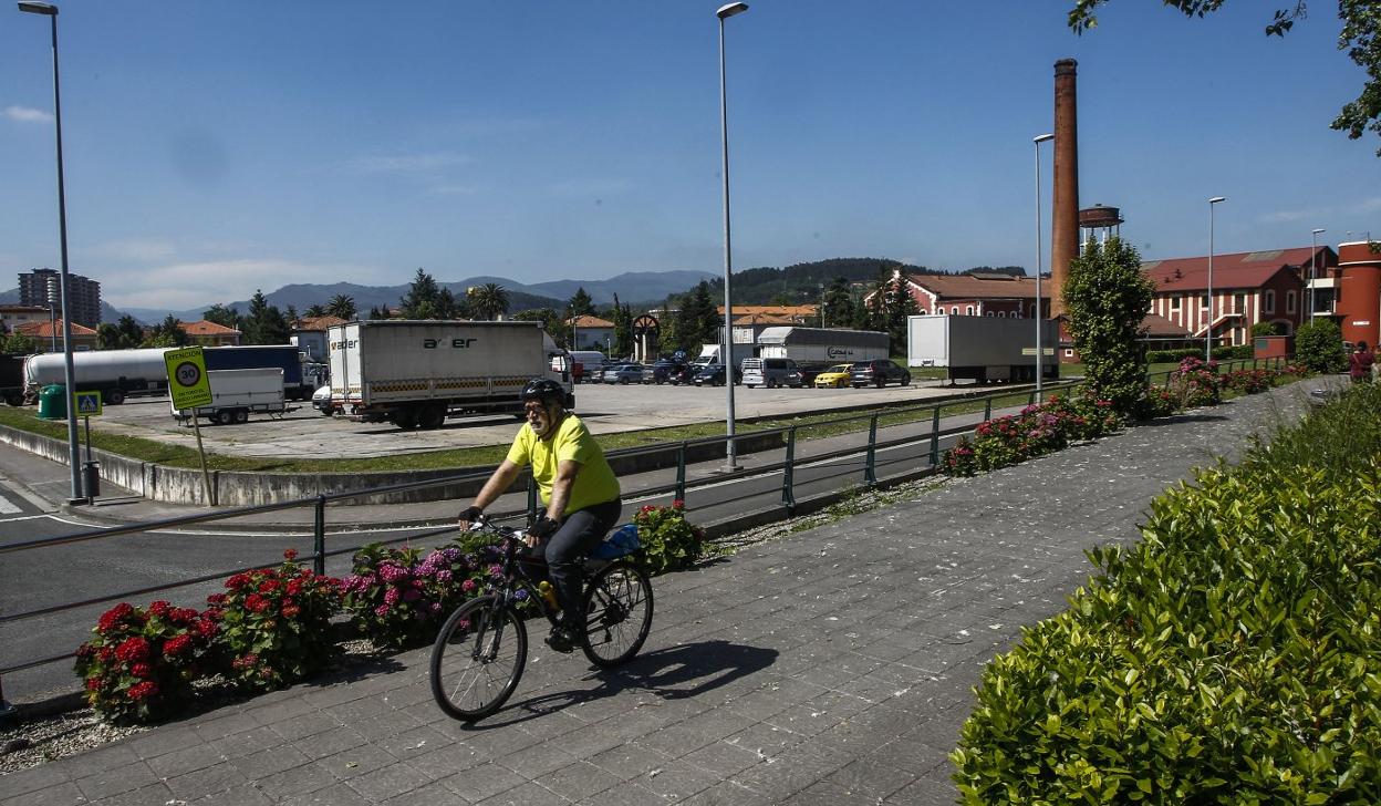 Un ciclista circula por delante de la parcela del aparcamiento para camiones de La Lechera. 