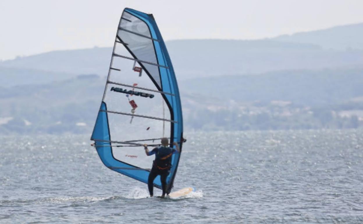 Un deportista practica windsurf en el pantano del Ebro.