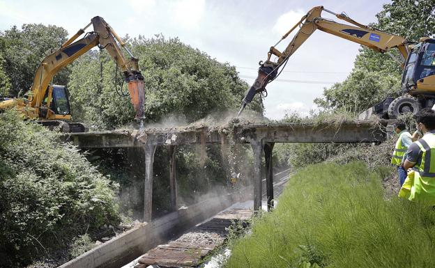 Dos máquinas pican para deriibar el puente sobre las vías de Los Tánagos.