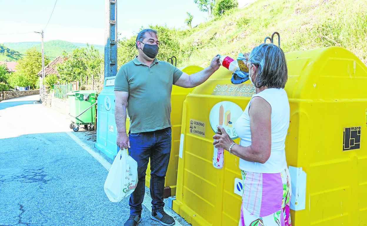 El alcalde, Eduardo Gutiérrez, y la vecina, Marisol Bustamente, depositan varios envases en el contenedor amarillo. 