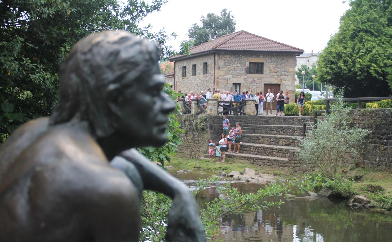 La figura del Hombre Pez de Liérganes en primer término y un grupo de turistas al fondo 