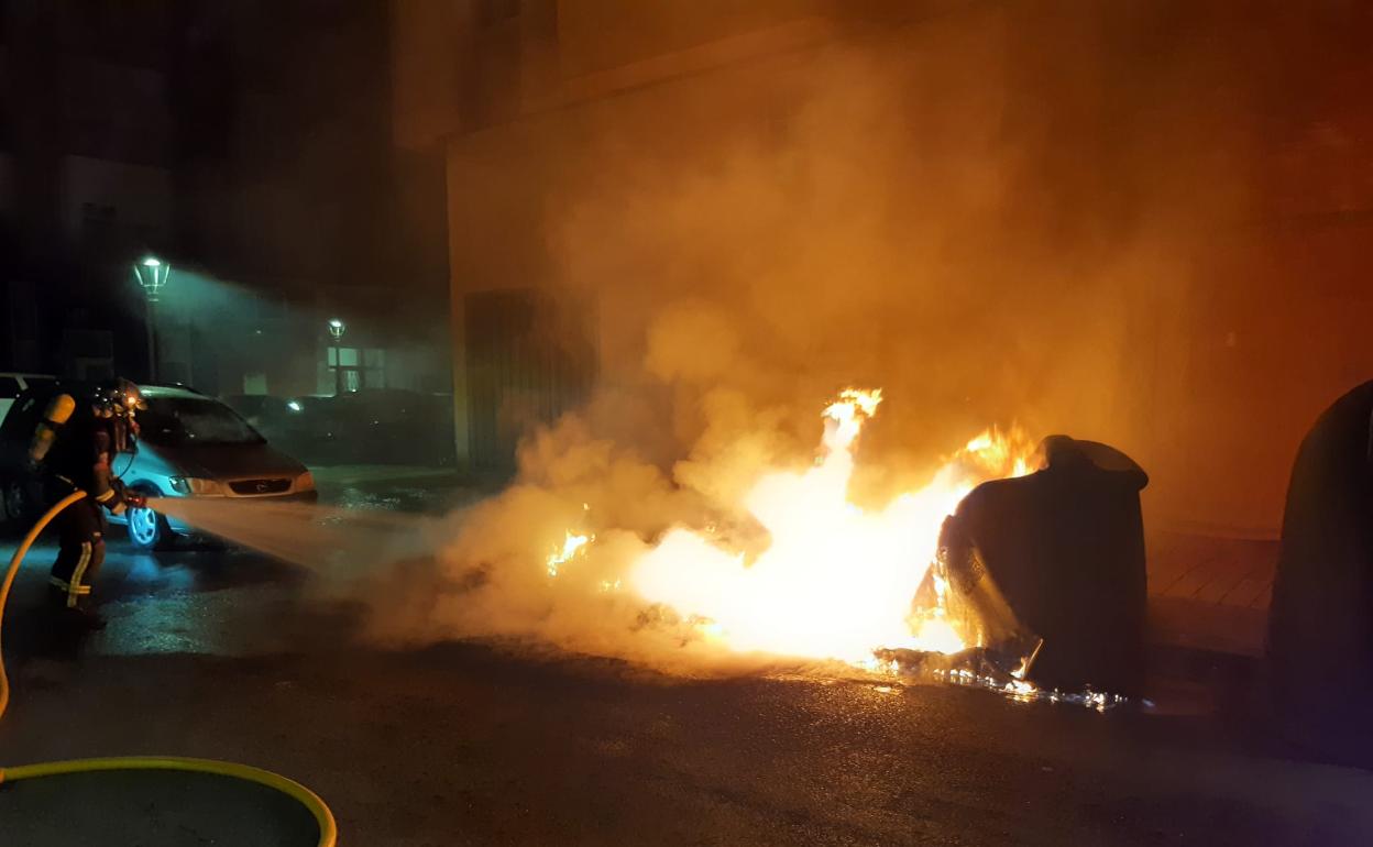 Un efectivo de bomberos sofoca el incendio durante la intervención de lunes por la madrugada, en el centro de Maliaño. 