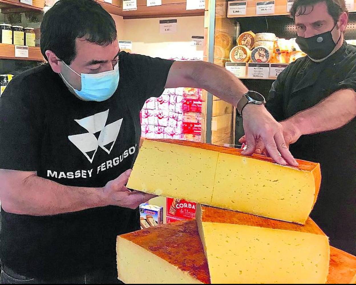 Tomás, a la izquierda, cortando el primer queso que sale al mercado. 