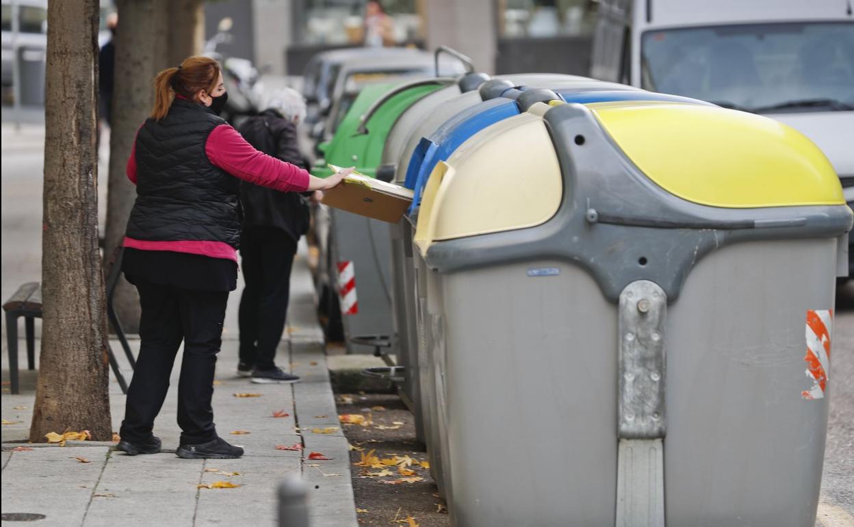 Una mujer usa un cubo de reciclaje en la calle Santa Lucía de Santander.