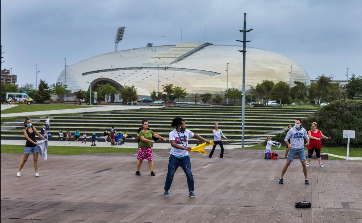 Un grupo participando en actividades de ocio en Las Llamas, con el Palacio de Deportes al fondo. 