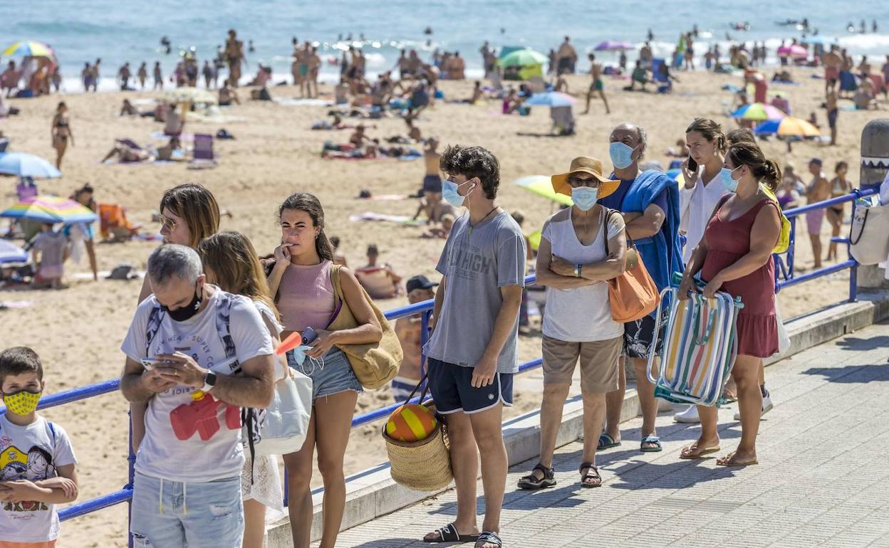 Gente con y sin mascarilla, ayer haciendo cola para poder entrar en la playa de El Sardinero.