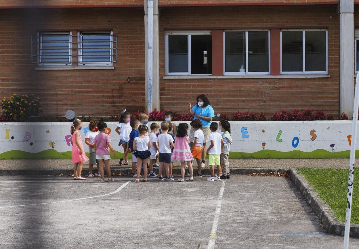 Una profesora habla con sus alumnos en el patio de un colegio durante el primer día de clase. 